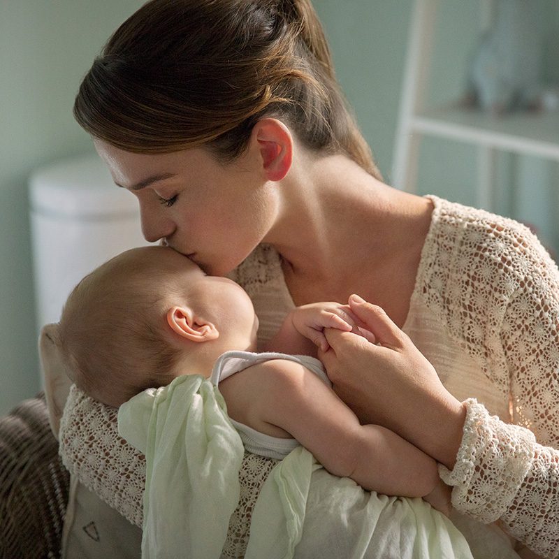 Mother kissing her baby in a tender moment at home