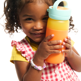 Toddler holding a stacked Munchkin cup tower with colorful rings in yellow, orange, and mint green