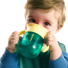 Toddler drinking from a green and yellow Munchkin sippy cup