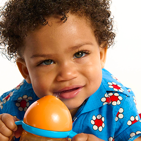 Toddler holding an orange Munchkin toy ball with blue band