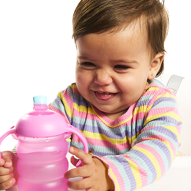Toddler holding a pink Munchkin stacked cup with handles, smiling at the camera
