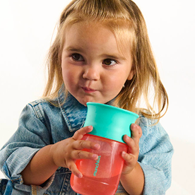 Toddler holding stacked Munchkin cups in turquoise and red.