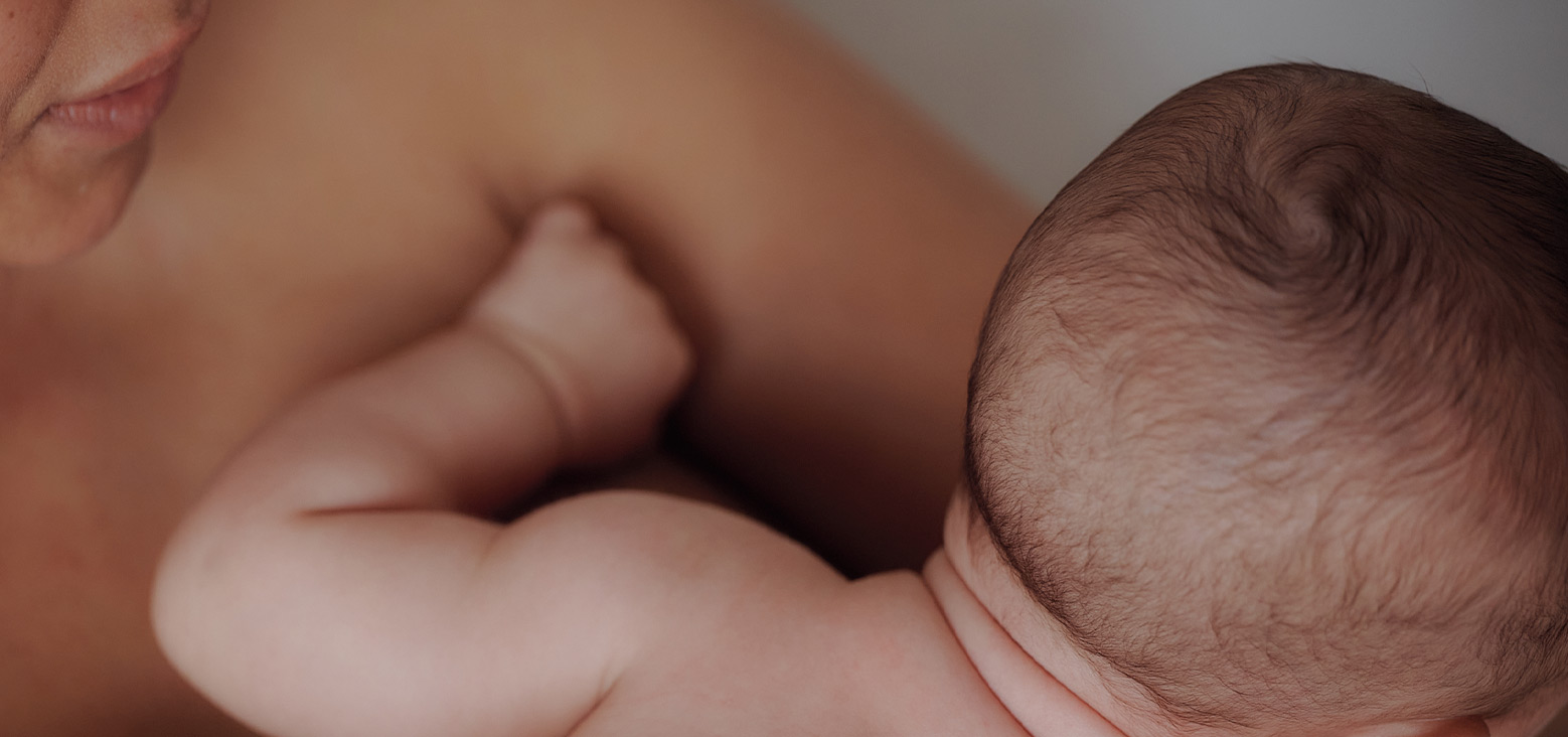 Newborn baby being held close to an adult's chest in a tender moment.