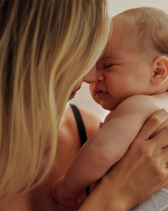 Parent holding newborn baby close to face in a tender moment