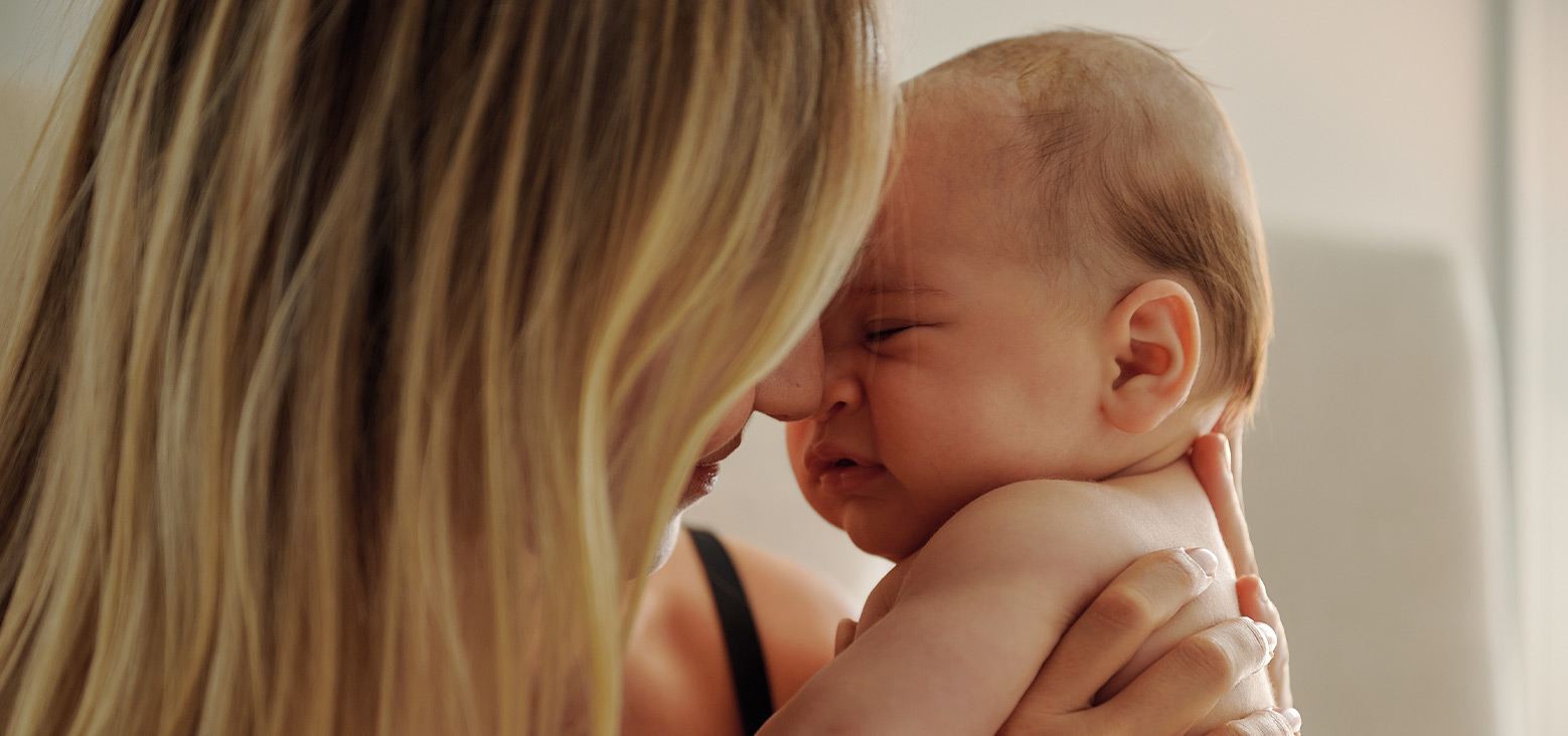 Parent holding newborn baby close, tender moment between caregiver and infant