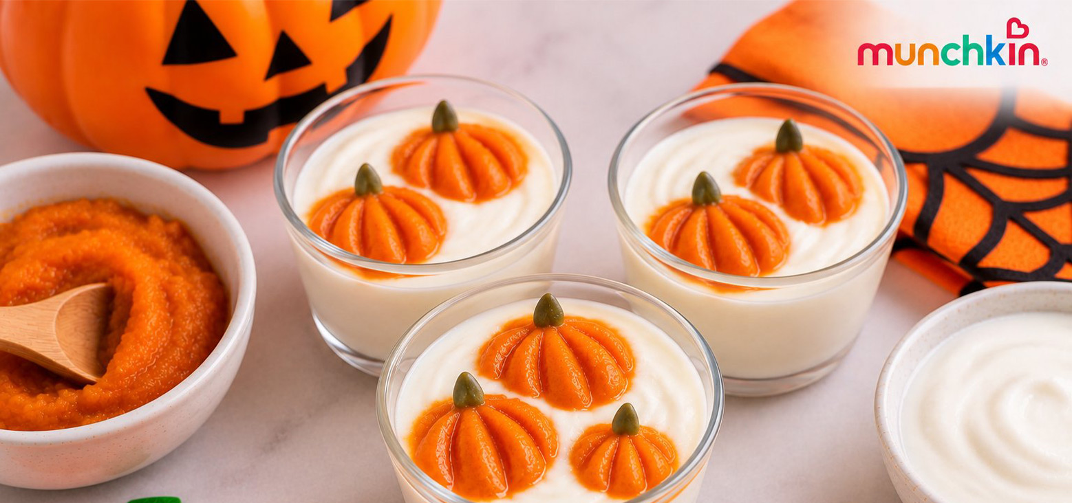 Munchkin logo with Halloween-themed baby food setup featuring pumpkin puree in bowls and yogurt cups topped with orange pumpkin shapes and green stems, surrounded by jack-o-lantern decorations.